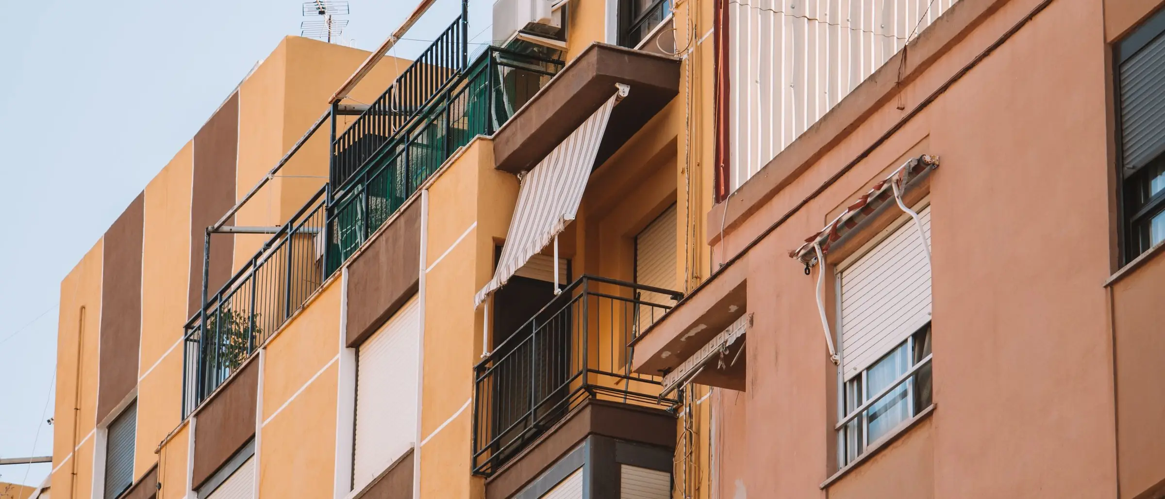 Fachada de un edificio de viviendas con balcones, toldos y persianas, en una calle española